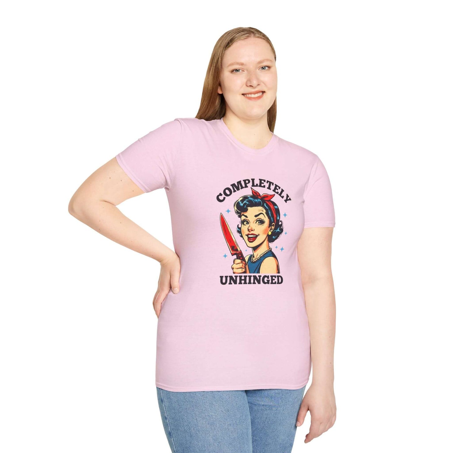 Smiling woman wearing a pink unisex t-shirt featuring a retro ‘Completely Unhinged’ design with a vintage-style woman holding a red knife and bold text.