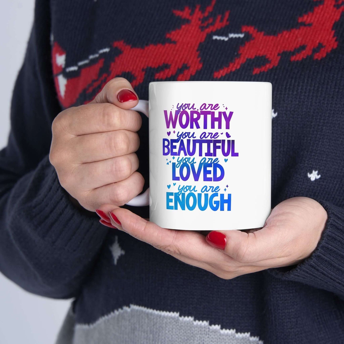 Hands holding a ceramic white mug with the quote "you are worthy, you are beautiful, you are loved, you are enough".