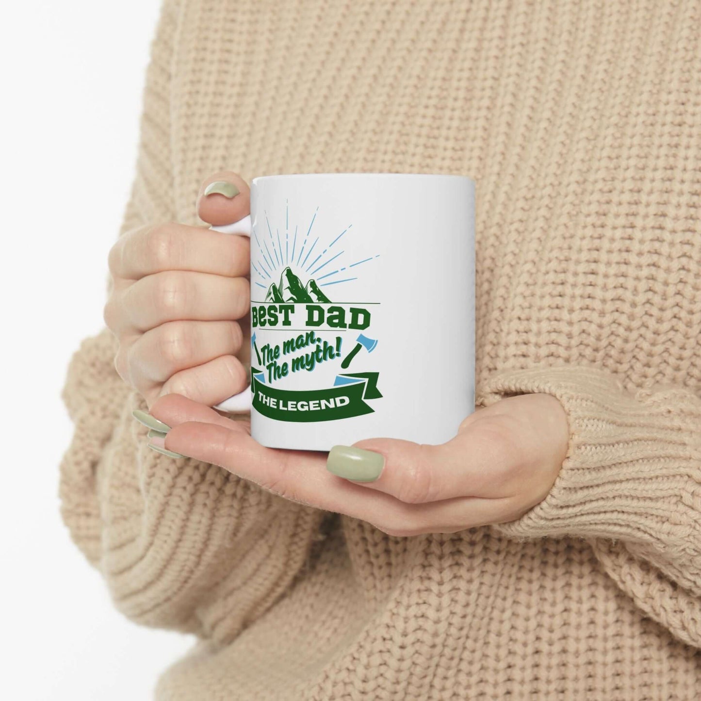 hand holding a White ceramic mug featuring a graphic design with green and blue text and decorative accents.