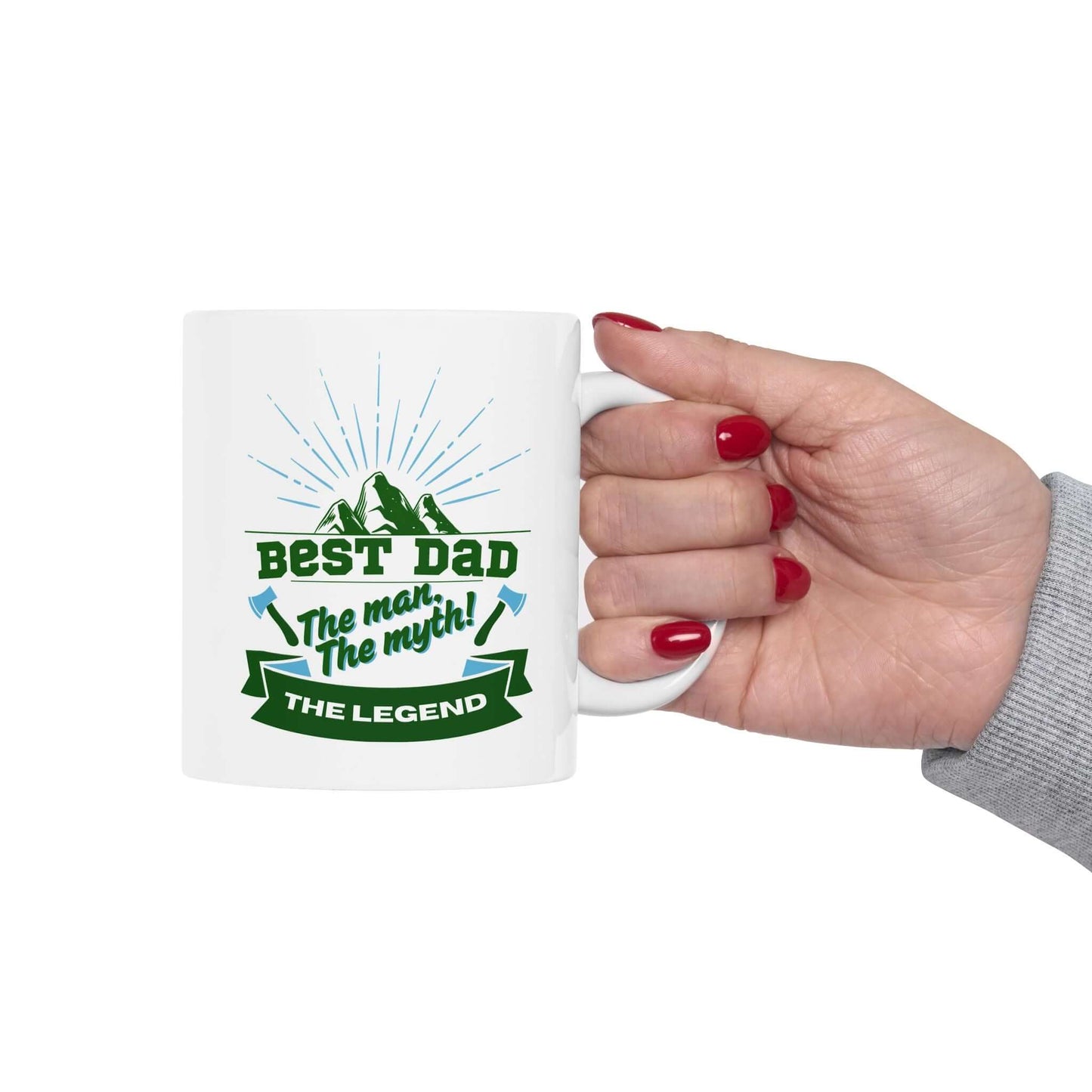 hand holding a white ceramic mug featuring a graphic design with green and blue text and decorative accents.