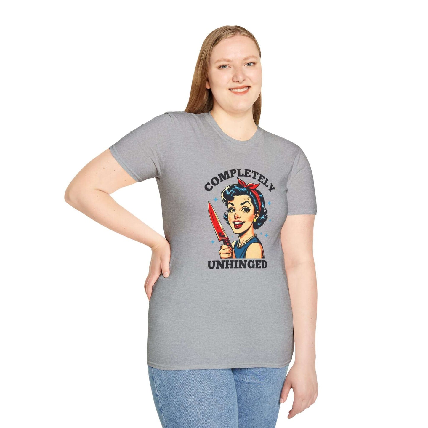 Smiling woman wearing a gray unisex t-shirt featuring a retro ‘Completely Unhinged’ design with a vintage-style woman holding a red knife and bold text.