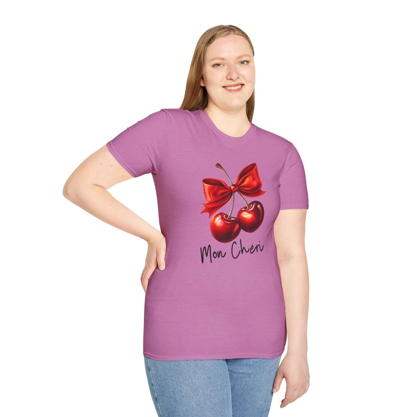 Smiling woman wearing a pink unisex t-shirt featuring a stylish ‘Mon Chéri’ design with two vibrant red cherries tied with a bow and elegant text.