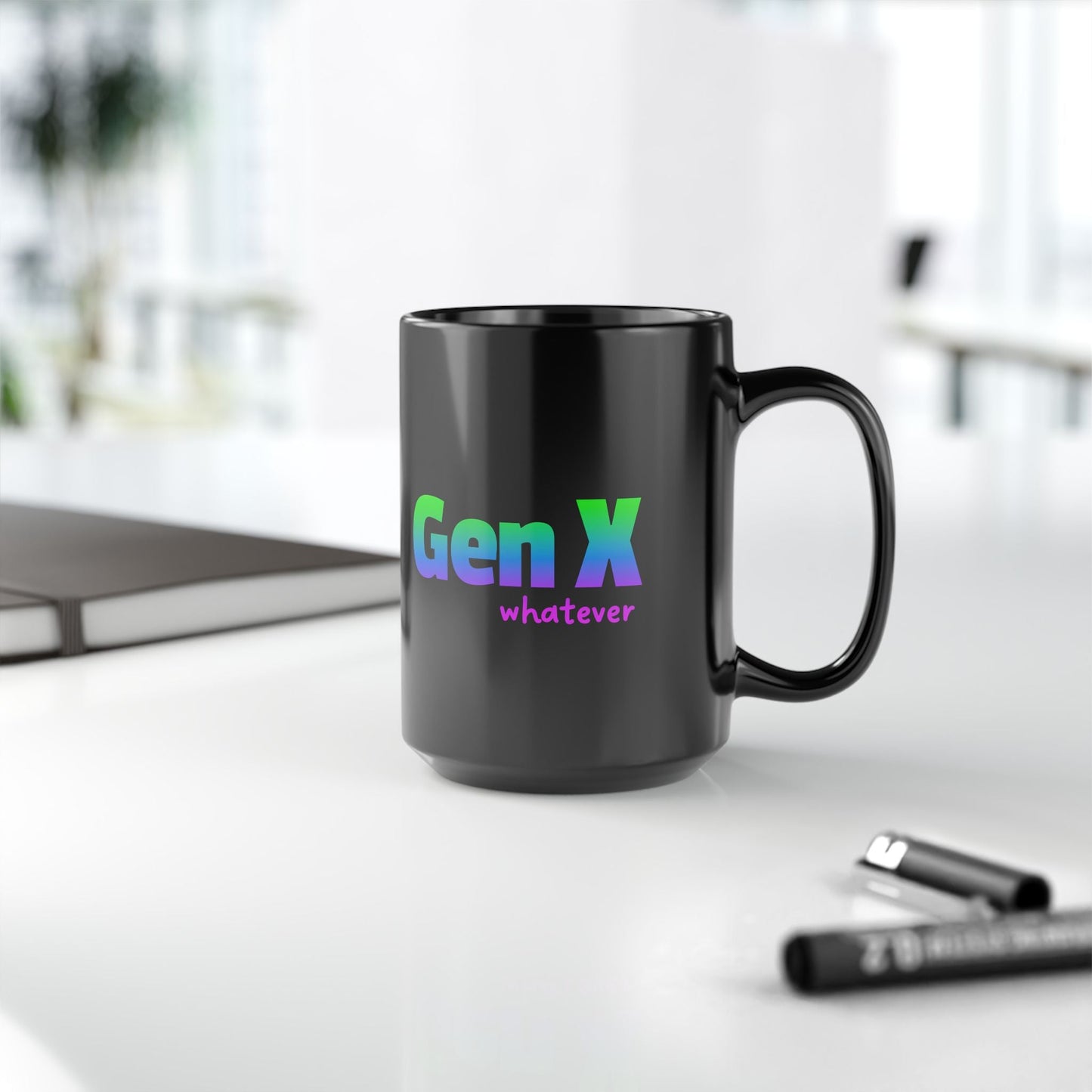 A sleek black ceramic coffee mug featuring the phrase “Gen X whatever” in bold gradient text transitioning from blue to green to purple. The mug is placed on a clean, modern office desk with a notebook and pens nearby, creating a professional yet stylish workspace setting.