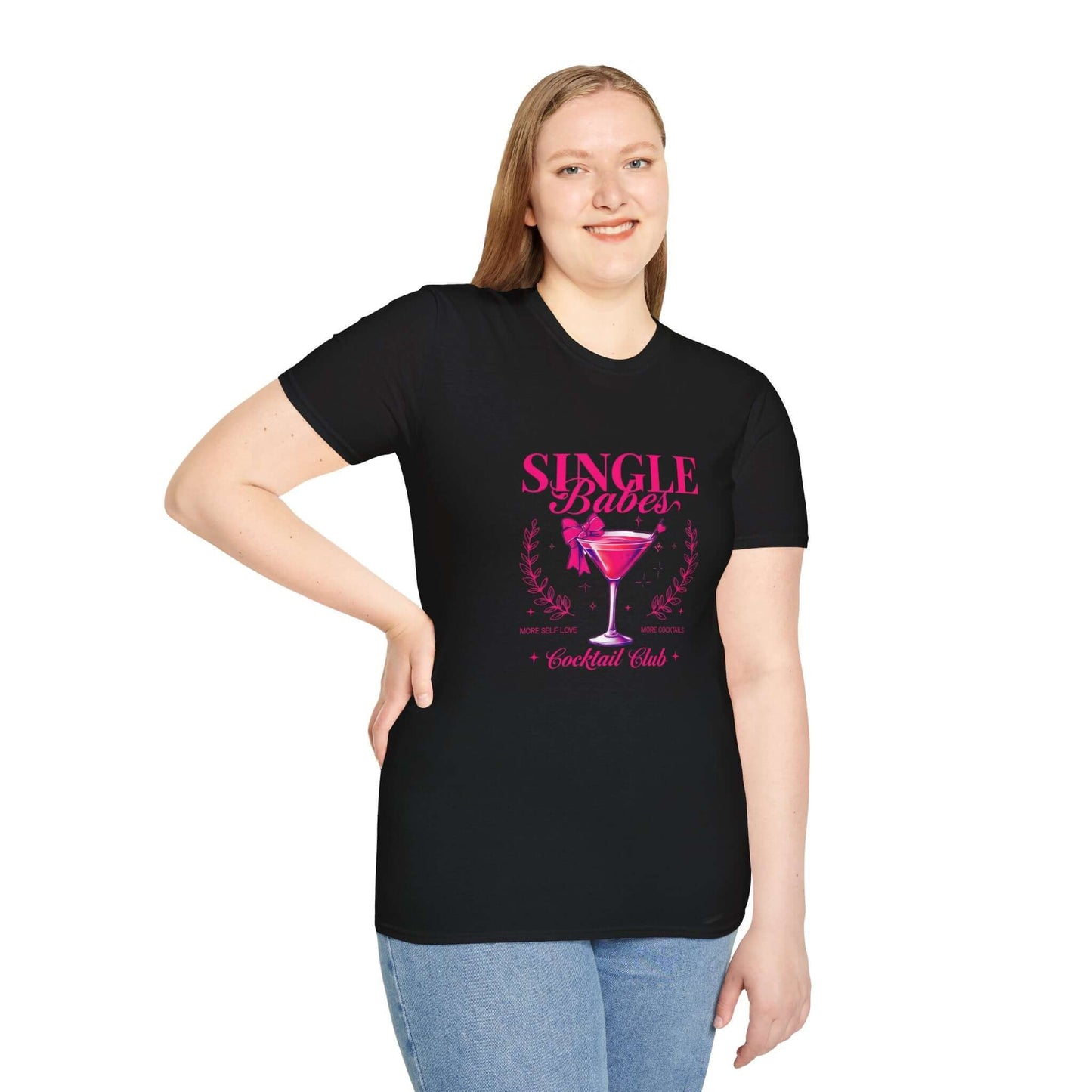 Smiling woman wearing a black t-shirt featuring the ‘Single Babes Cocktail Club’ design with a pink cocktail glass, floral accents, and elegant script text.