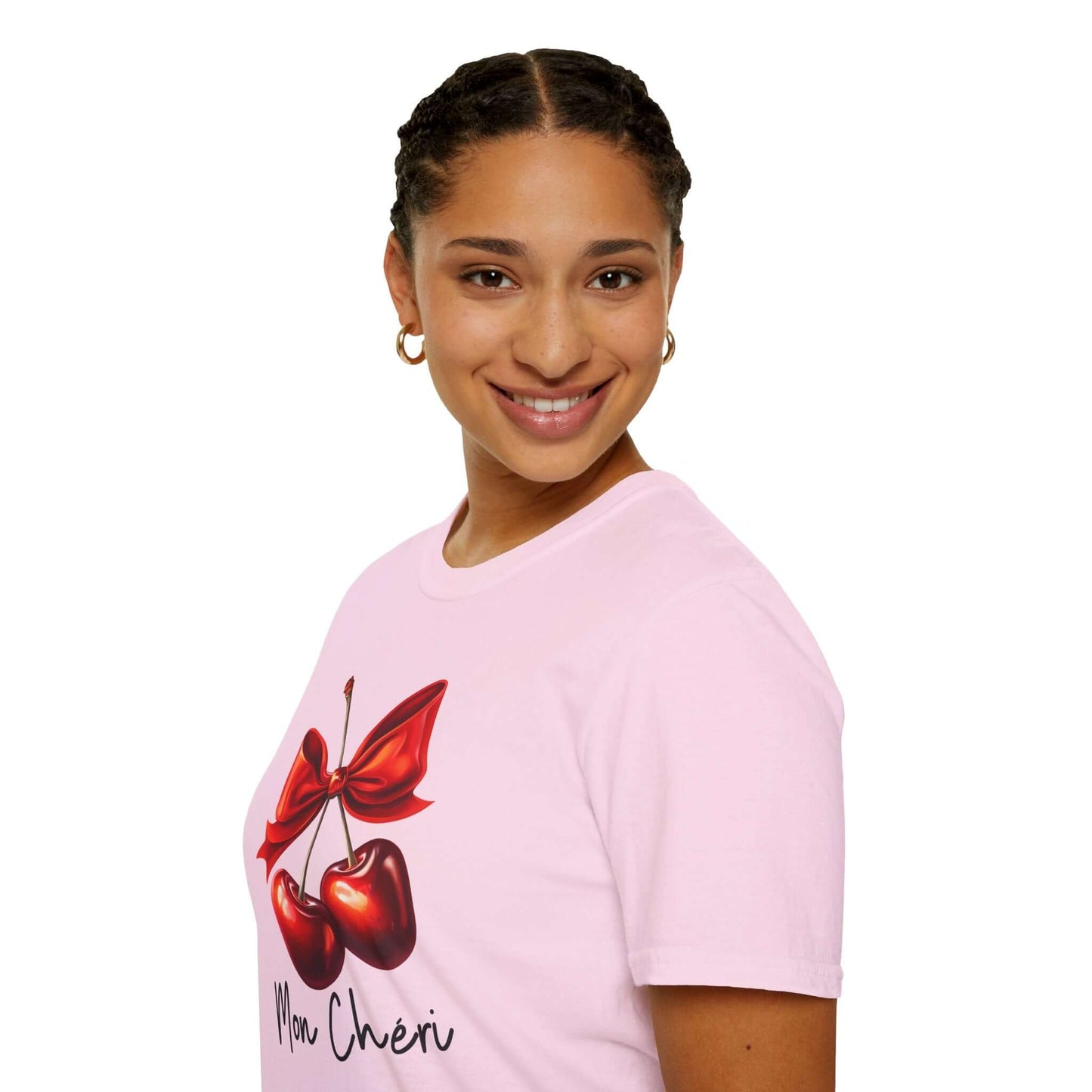 Smiling woman wearing a light pink unisex t-shirt featuring a stylish ‘Mon Chéri’ design with two vibrant red cherries tied with a bow and elegant text.