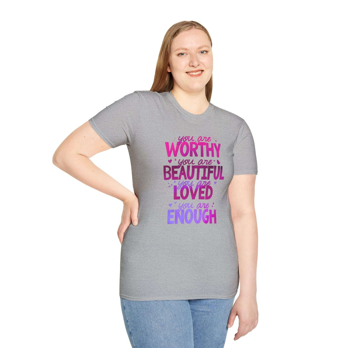 Smiling woman wearing a gray unisex t-shirt featuring an inspirational design with the text ‘You are Worthy, You are Beautiful, You are Loved, You are Enough’ in pink and purple.