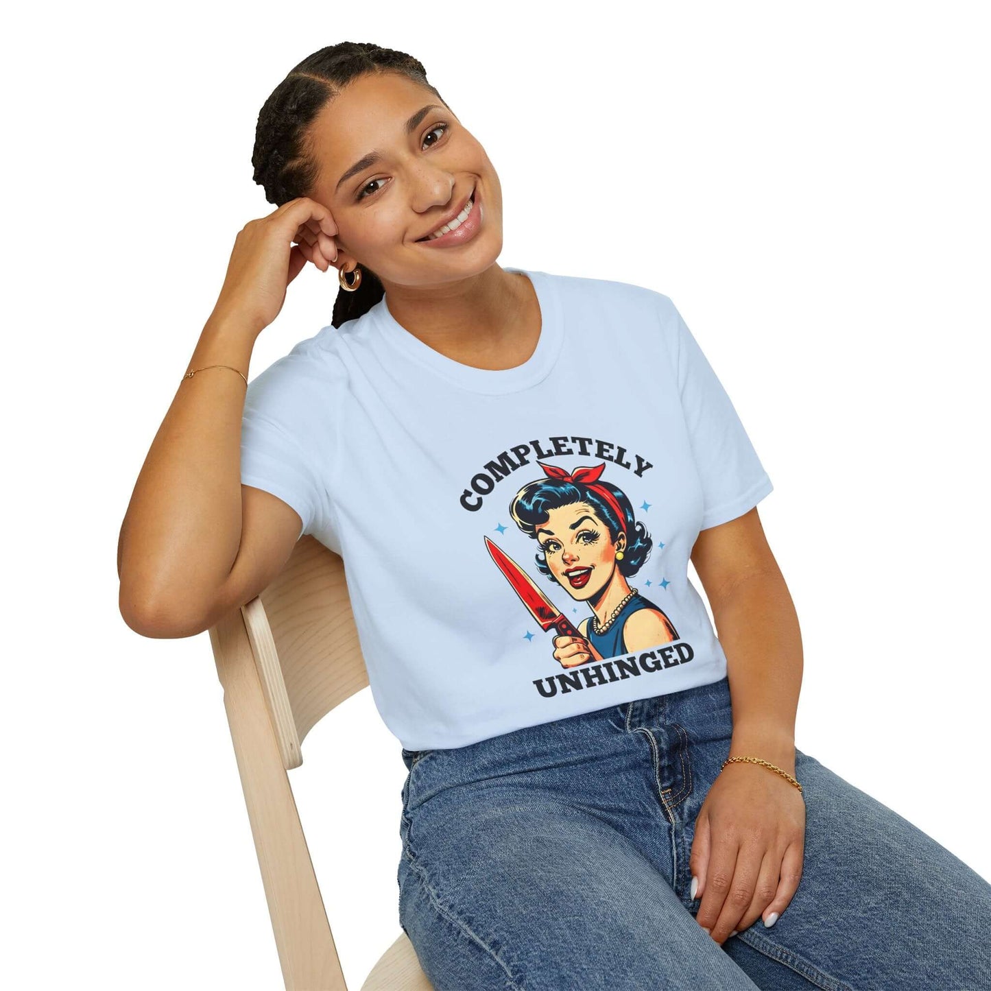 Smiling woman wearing a light blue unisex t-shirt featuring a retro ‘Completely Unhinged’ design with a vintage-style woman holding a red knife and bold text.