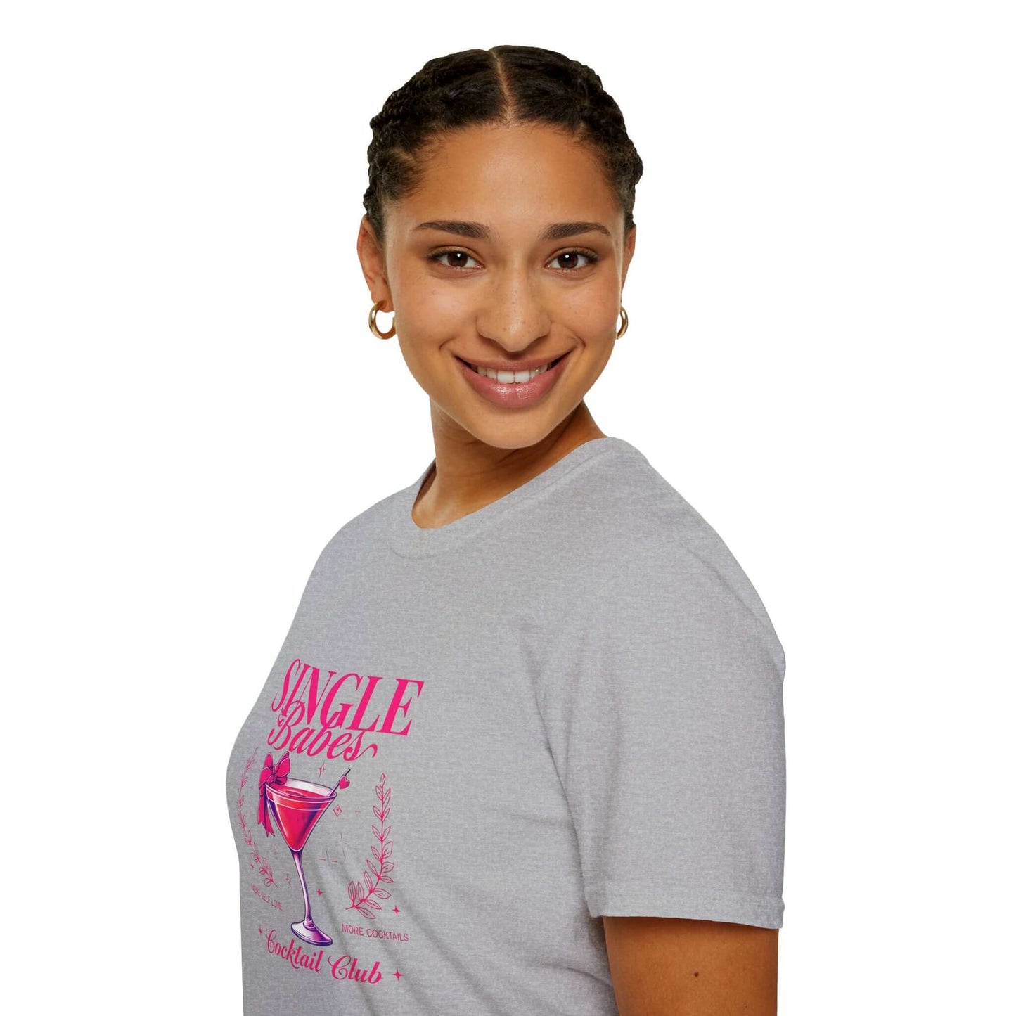 Smiling woman wearing a gray t-shirt featuring the ‘Single Babes Cocktail Club’ design with a pink cocktail glass, floral accents, and elegant script text.