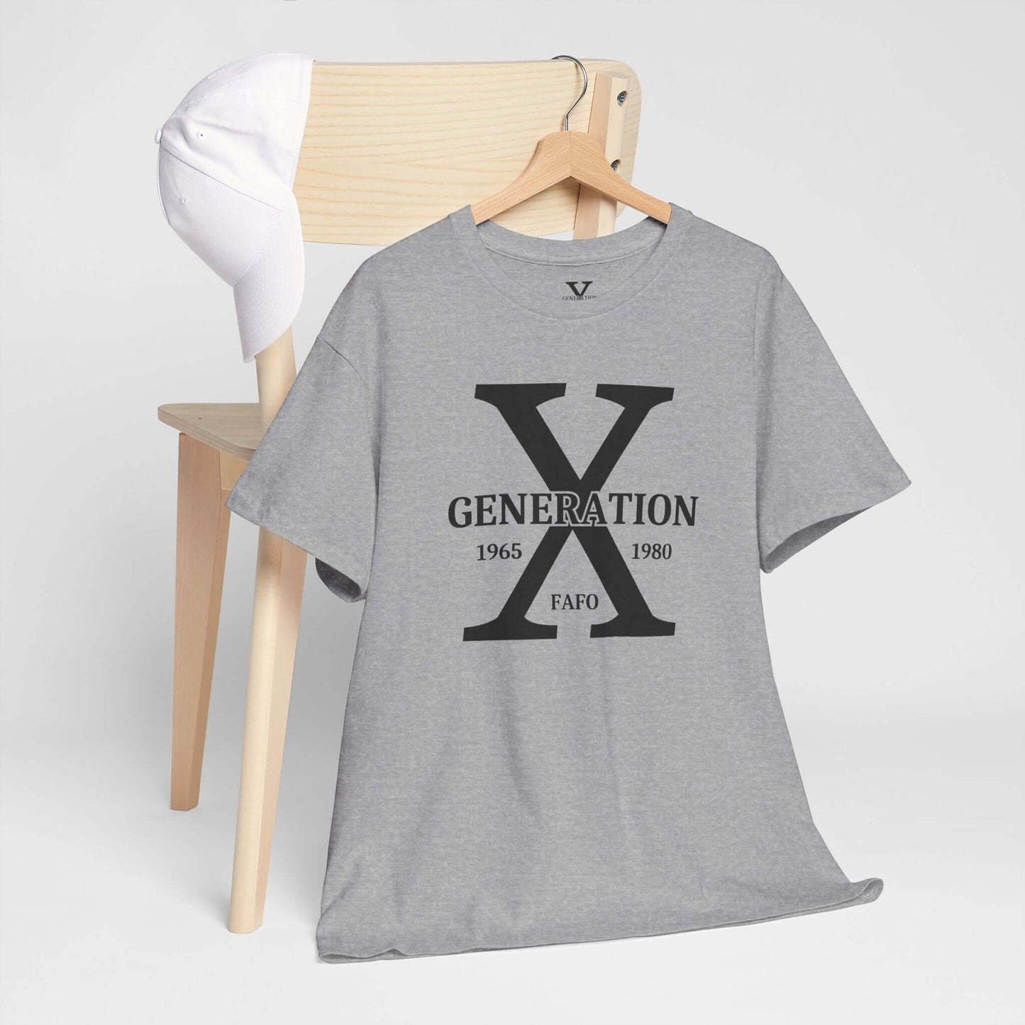 A gray t-shirt featuring a bold “GENERATION X” design with “FAFO” underneath is draped over a wooden chair. A white baseball cap rests on the chair’s back, creating a stylish and casual display.