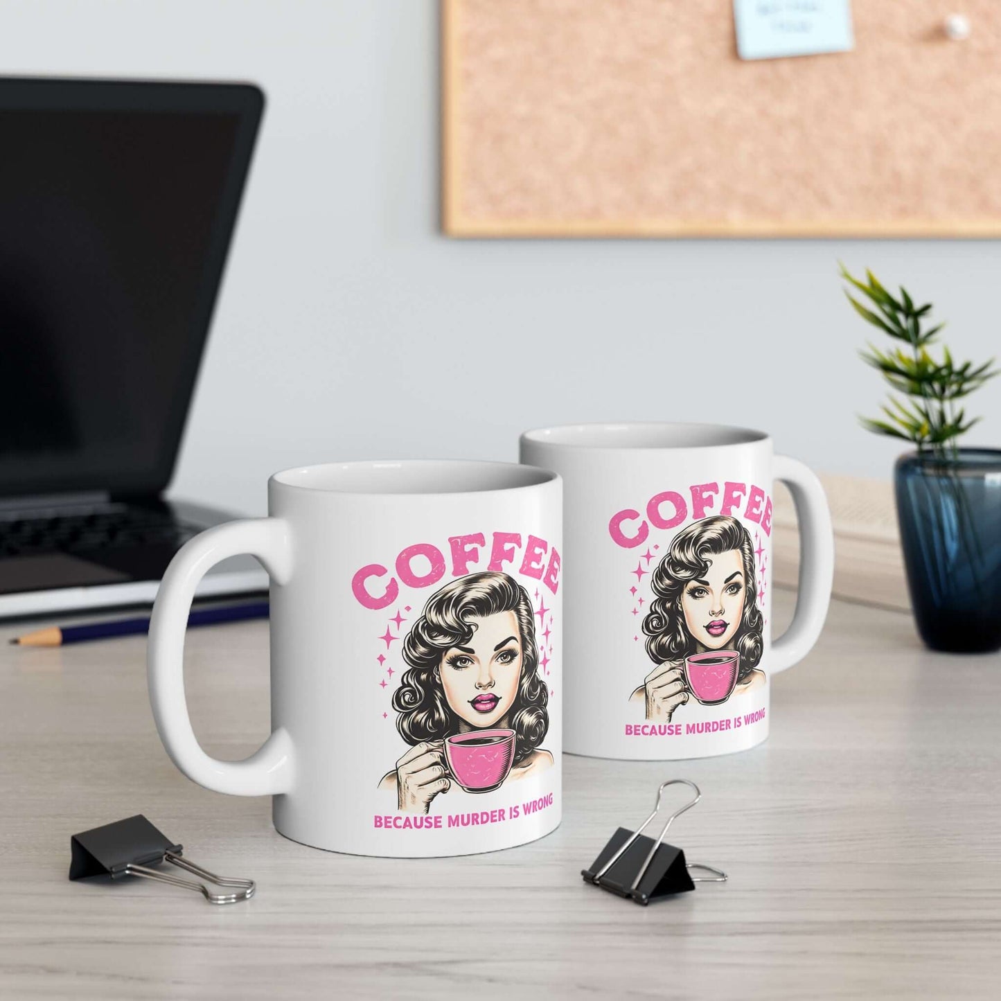 Two white ceramic mugs with a retro ‘Coffee - Because Murder Is Wrong’ design in pink, featuring a vintage-style woman holding a coffee cup, displayed on a desk.