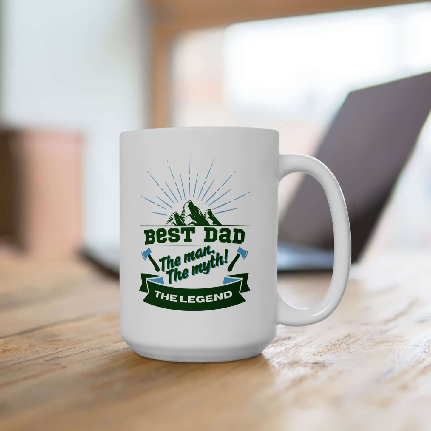 White ceramic mug featuring a graphic design with green and blue text and decorative accents; sitting on a desk.