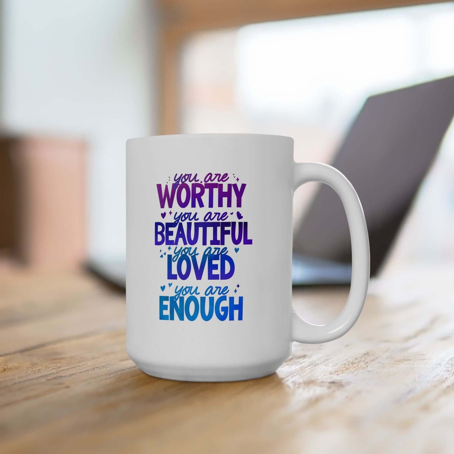 a ceramic white mug with the quote "you are worthy, you are beautiful, you are loved, you are enough", sitting on a desk.