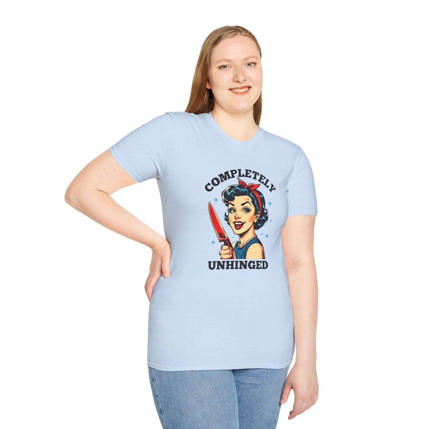 Smiling woman wearing a light blue unisex t-shirt featuring a retro ‘Completely Unhinged’ design with a vintage-style woman holding a red knife and bold text.