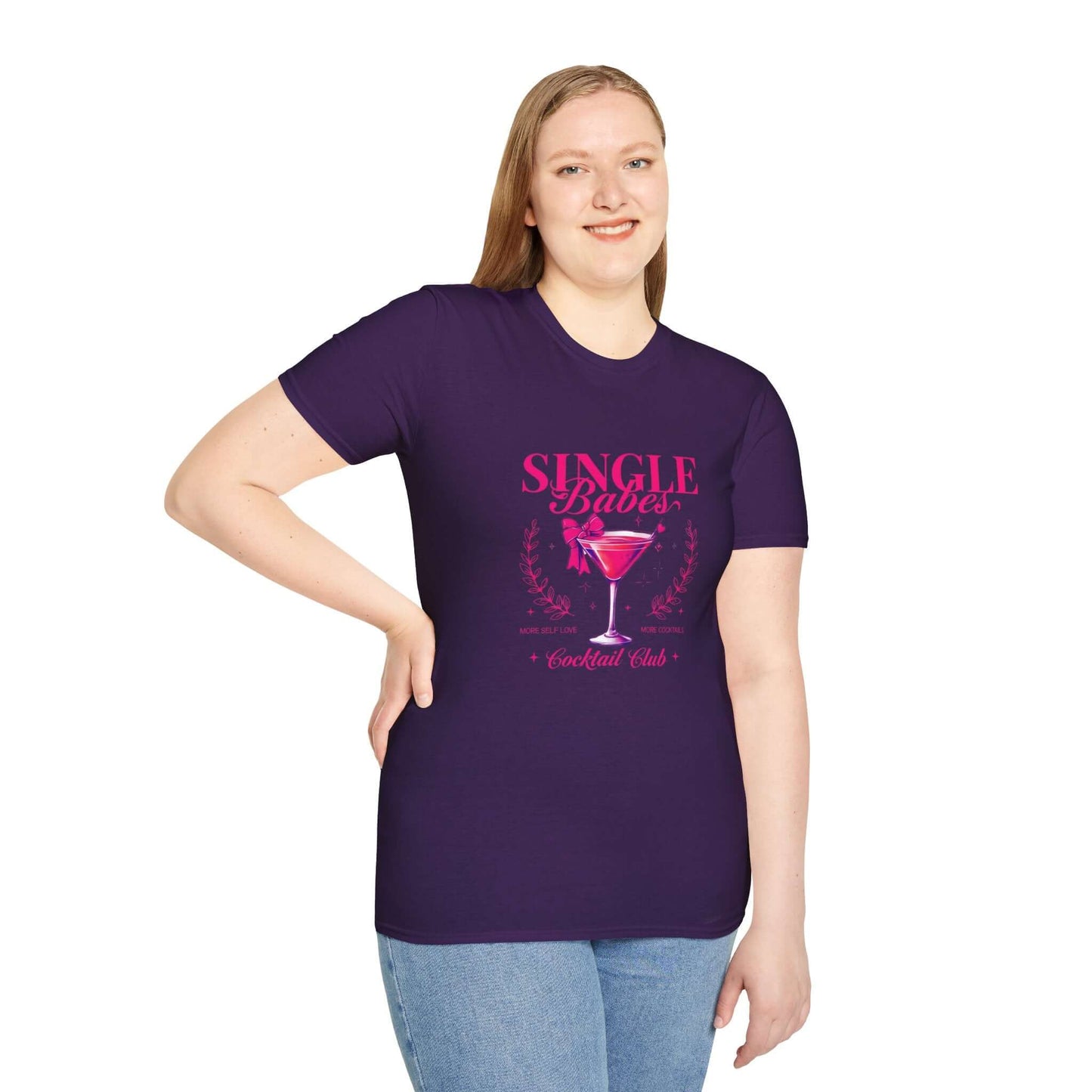 Smiling woman wearing a purple t-shirt featuring the ‘Single Babes Cocktail Club’ design with a pink cocktail glass, floral accents, and elegant script text.