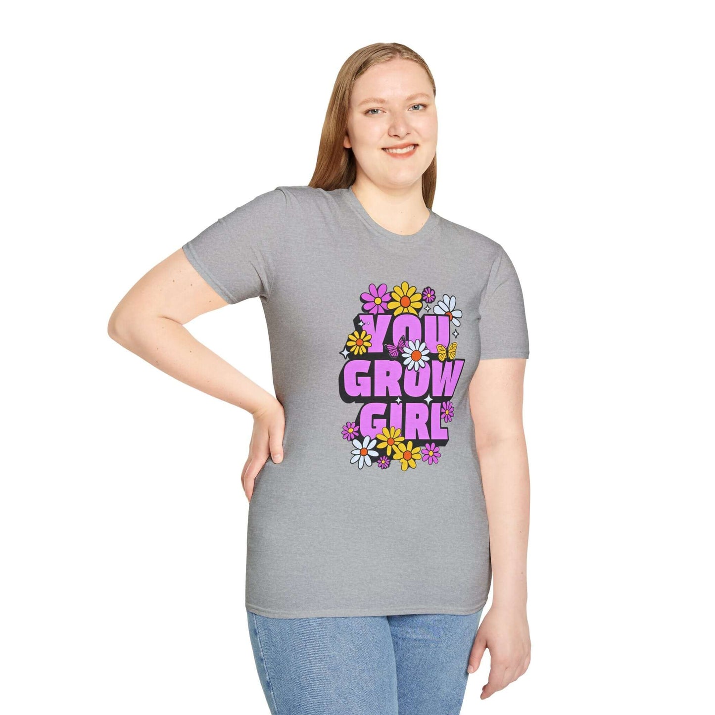 Woman wearing a gray t-shirt displaying the phrase ‘YOU GROW GIRL’ in bold purple letters surrounded by colorful flowers.