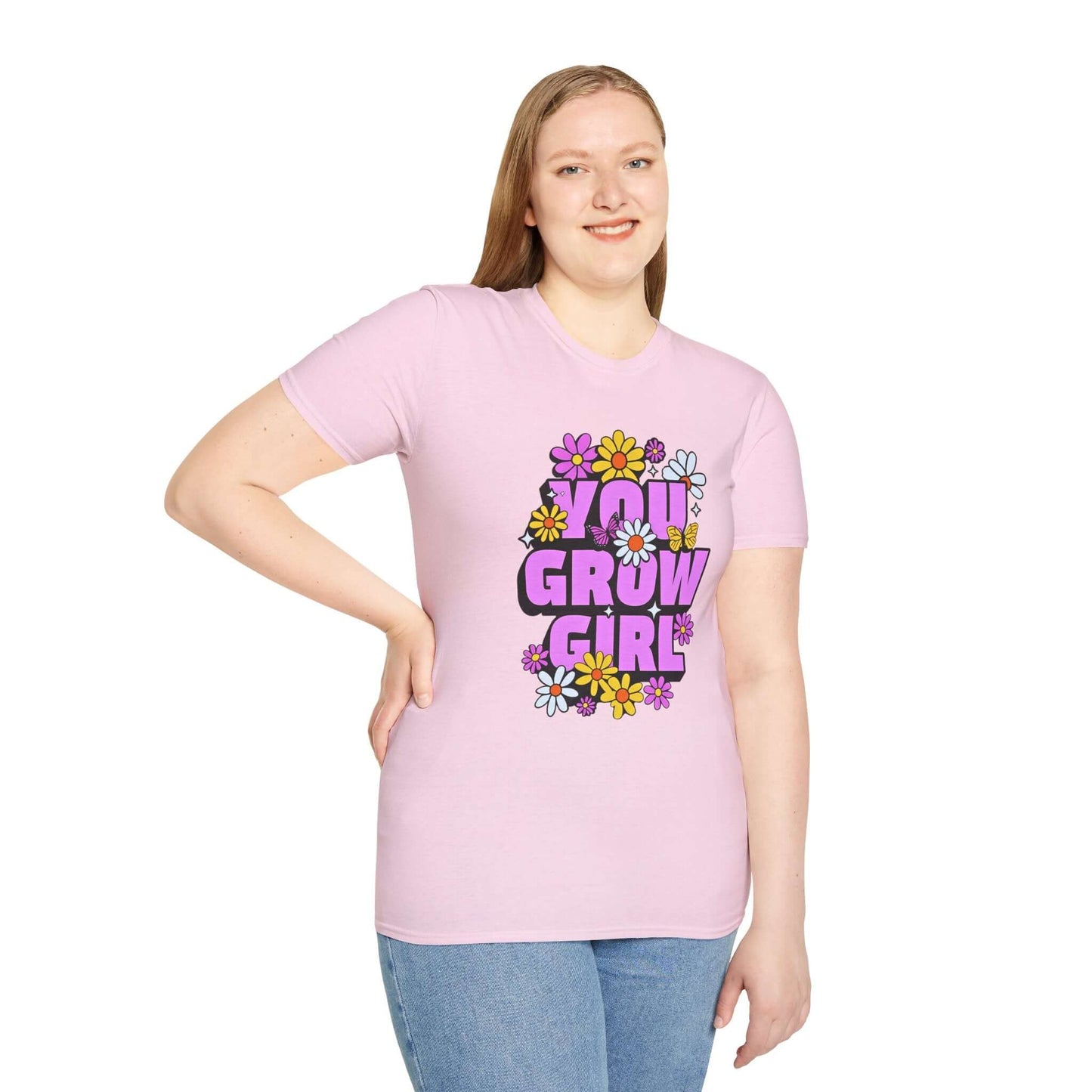Woman wearing a light pink t-shirt displaying the phrase ‘YOU GROW GIRL’ in bold purple letters surrounded by colorful flowers.