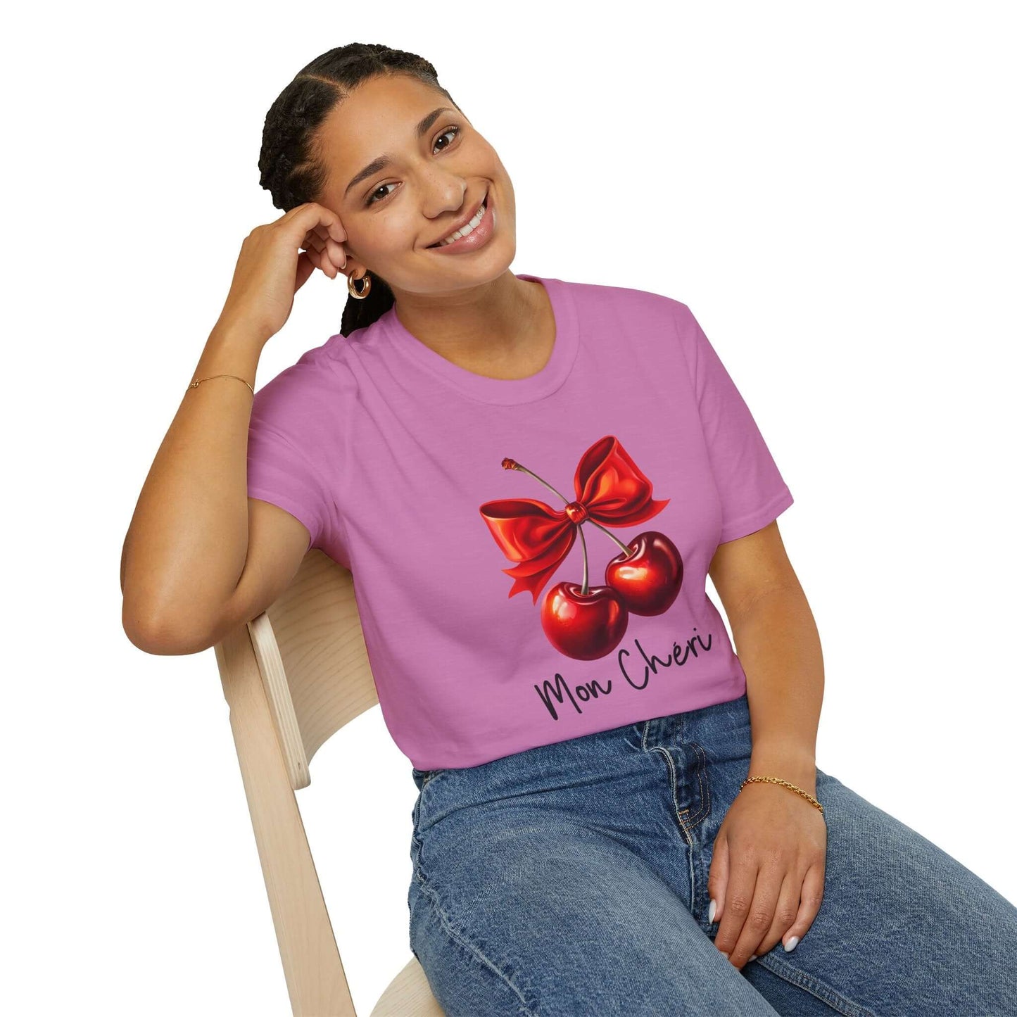 Smiling woman wearing a pink unisex t-shirt featuring a stylish ‘Mon Chéri’ design with two vibrant red cherries tied with a bow and elegant text.