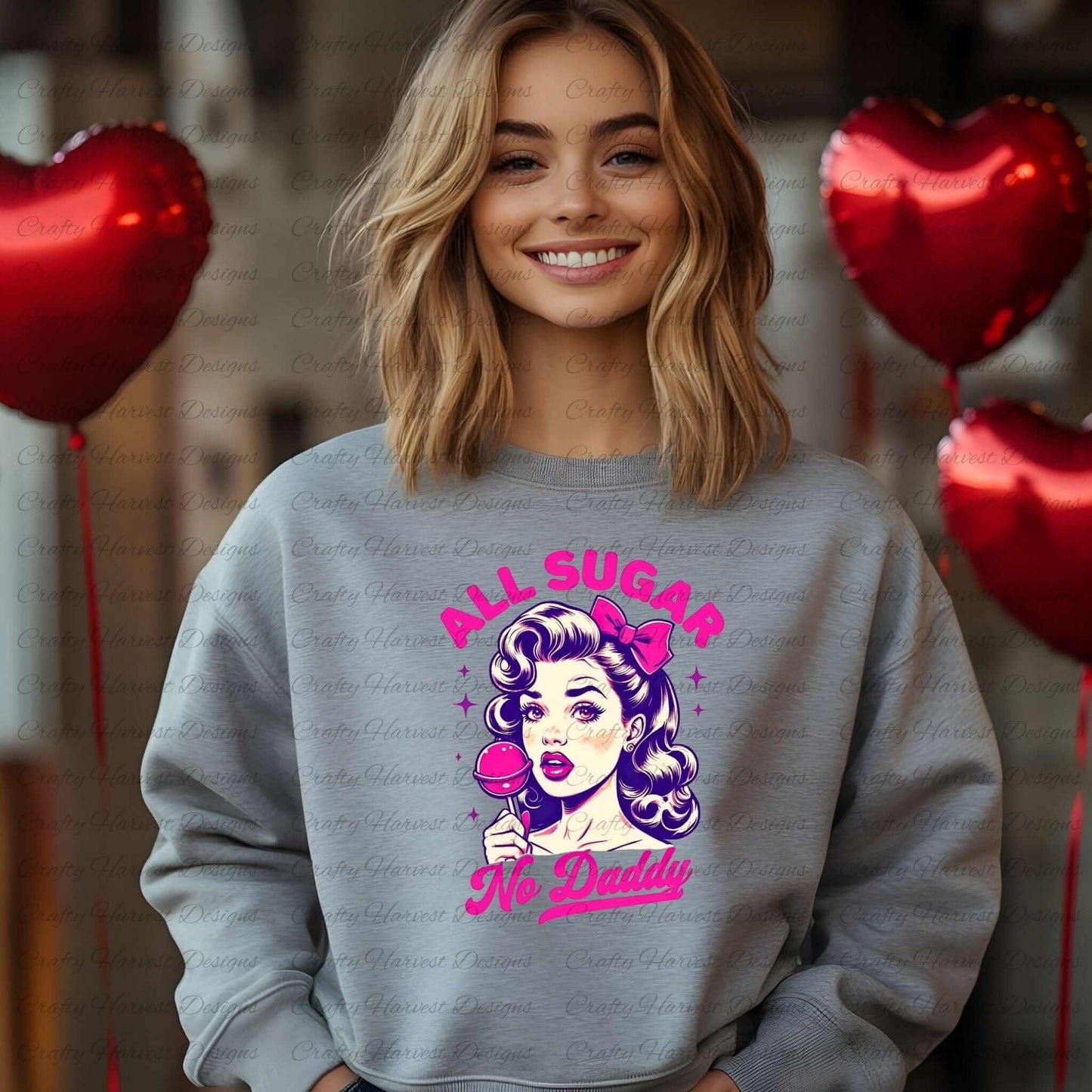 Gray sweatshirt featuring a retro-inspired digital design of a vintage-style woman holding a lollipop, paired with the bold text ‘All Sugar No Daddy’ in pink and purple. The sweatshirt is worn by a smiling person, with red heart-shaped balloons in the background, showcasing its use as a cozy and stylish apparel option.