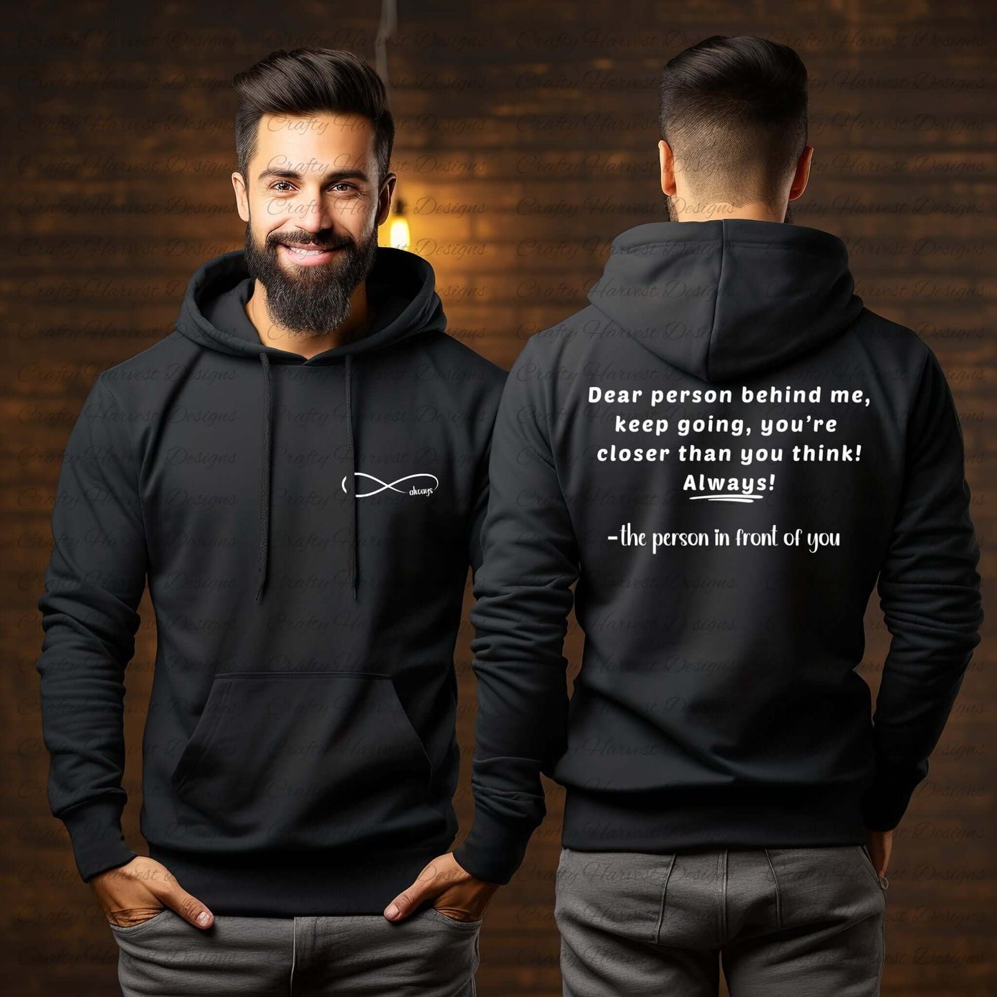 Model wearing a black hoodie featuring the “Dear person behind me” design. The front displays an infinity symbol with the word “always” on the left chest pocket area in white text. The back shows the quote: “Dear person behind me, keep going, you're closer than you think! Always! –the person in front of you” in white text. The model is smiling in a warm, indoor setting with soft lighting.