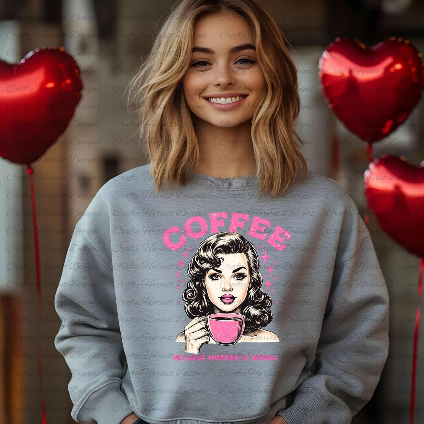 Smiling woman wearing a gray sweatshirt featuring a retro-inspired digital design of a vintage-style woman holding a coffee cup, with the humorous text ‘Coffee - Because Murder Is Wrong’ in bold pink letters. Red heart-shaped balloons are visible in the background, emphasizing the design’s playful and cozy appeal.