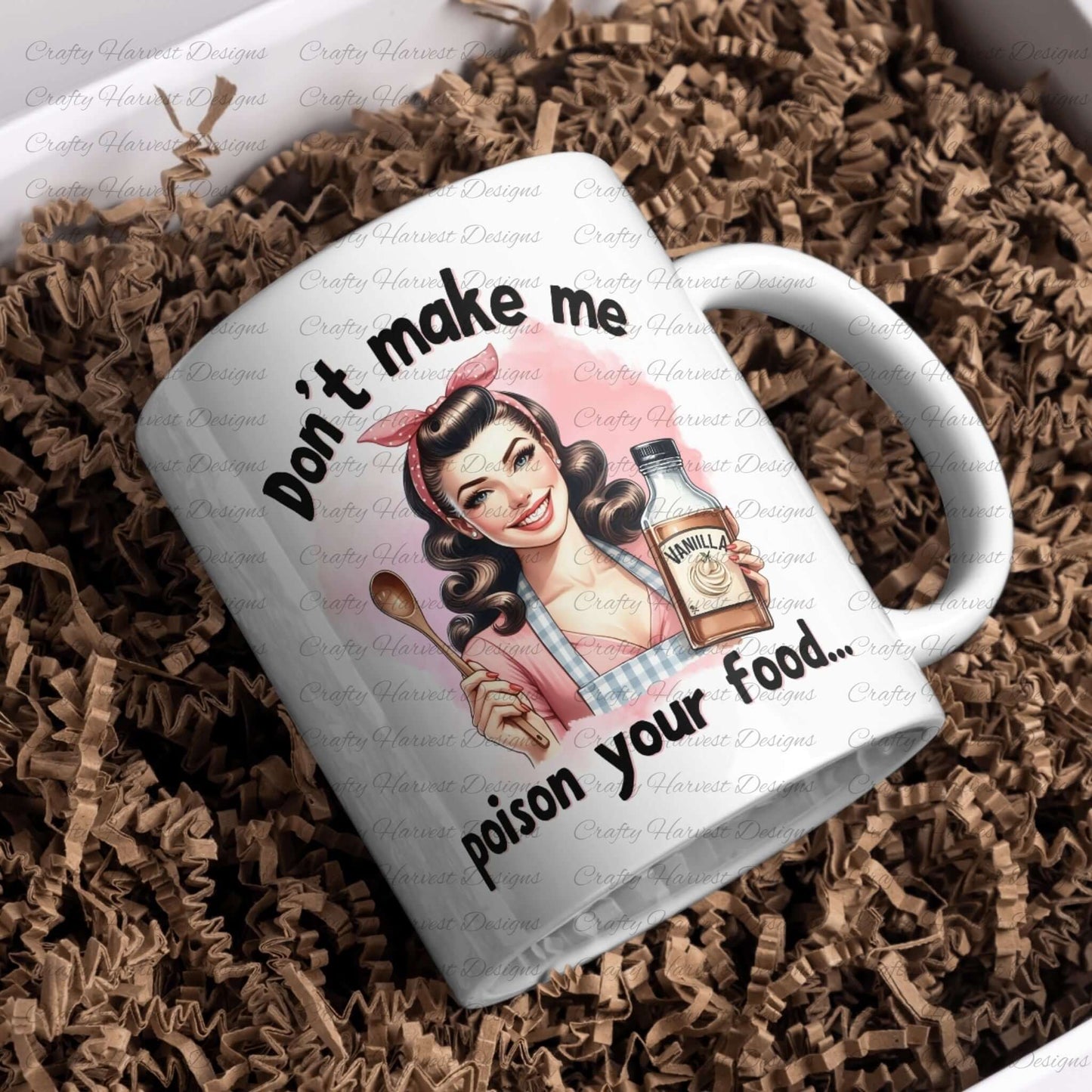 White ceramic mug placed on brown crinkle paper, featuring a vintage-style design of a smiling retro housewife holding a wooden spoon and a bottle labeled “Vanilla.” The text around the illustration reads, “Don’t make me poison your food…