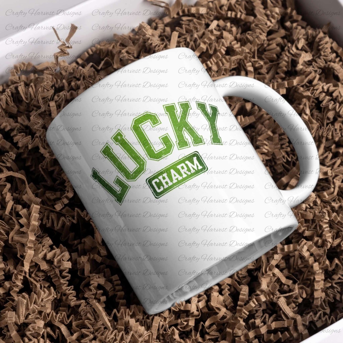 White ceramic mug featuring the ‘Lucky Charm’ St. Patrick’s Day design in bold green text. The mug is placed on a bed of brown crinkle paper for a festive presentation.