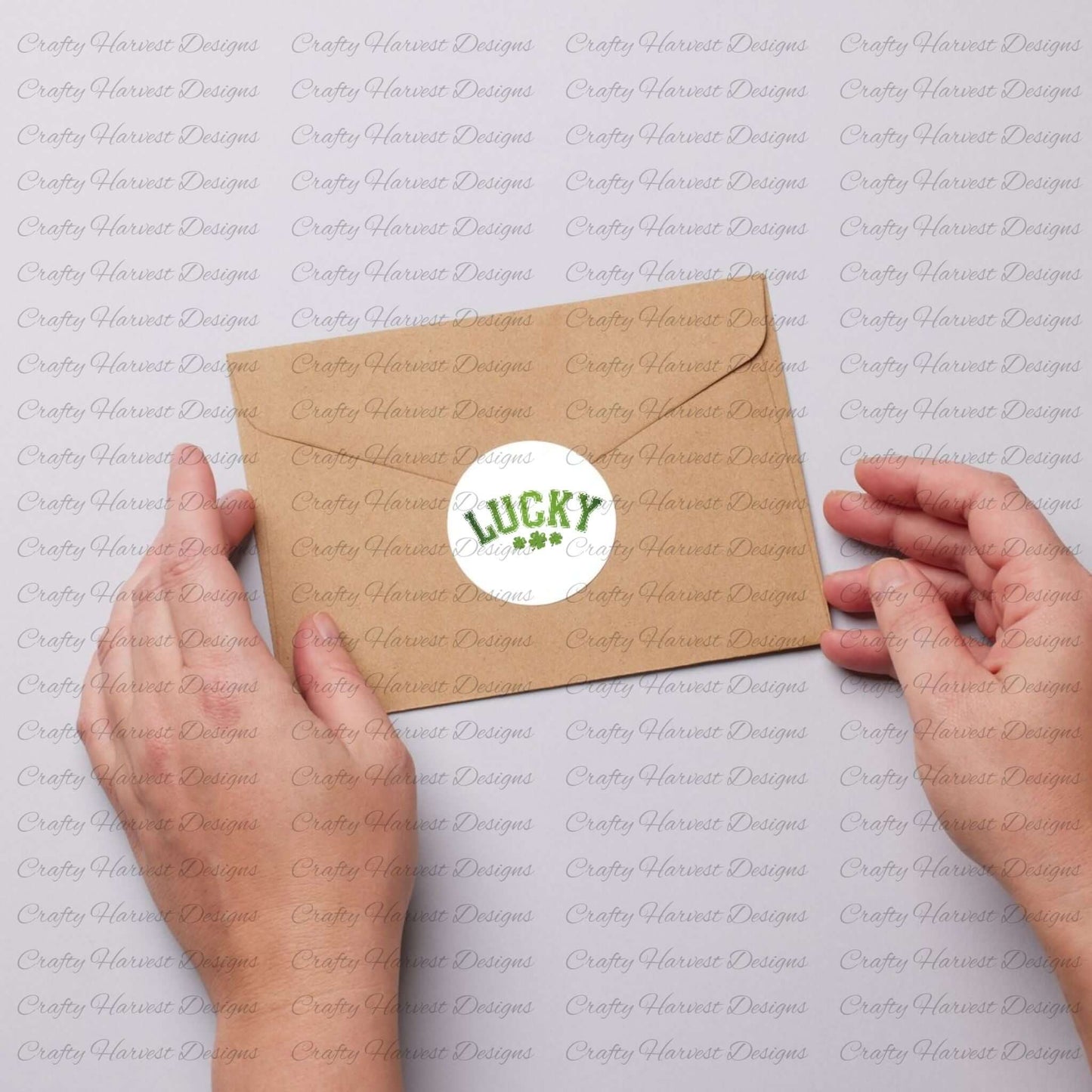 Two hands holding a kraft envelope sealed with a circular sticker that displays the word ‘Lucky’ in green, featuring a festive St. Patrick’s Day theme.