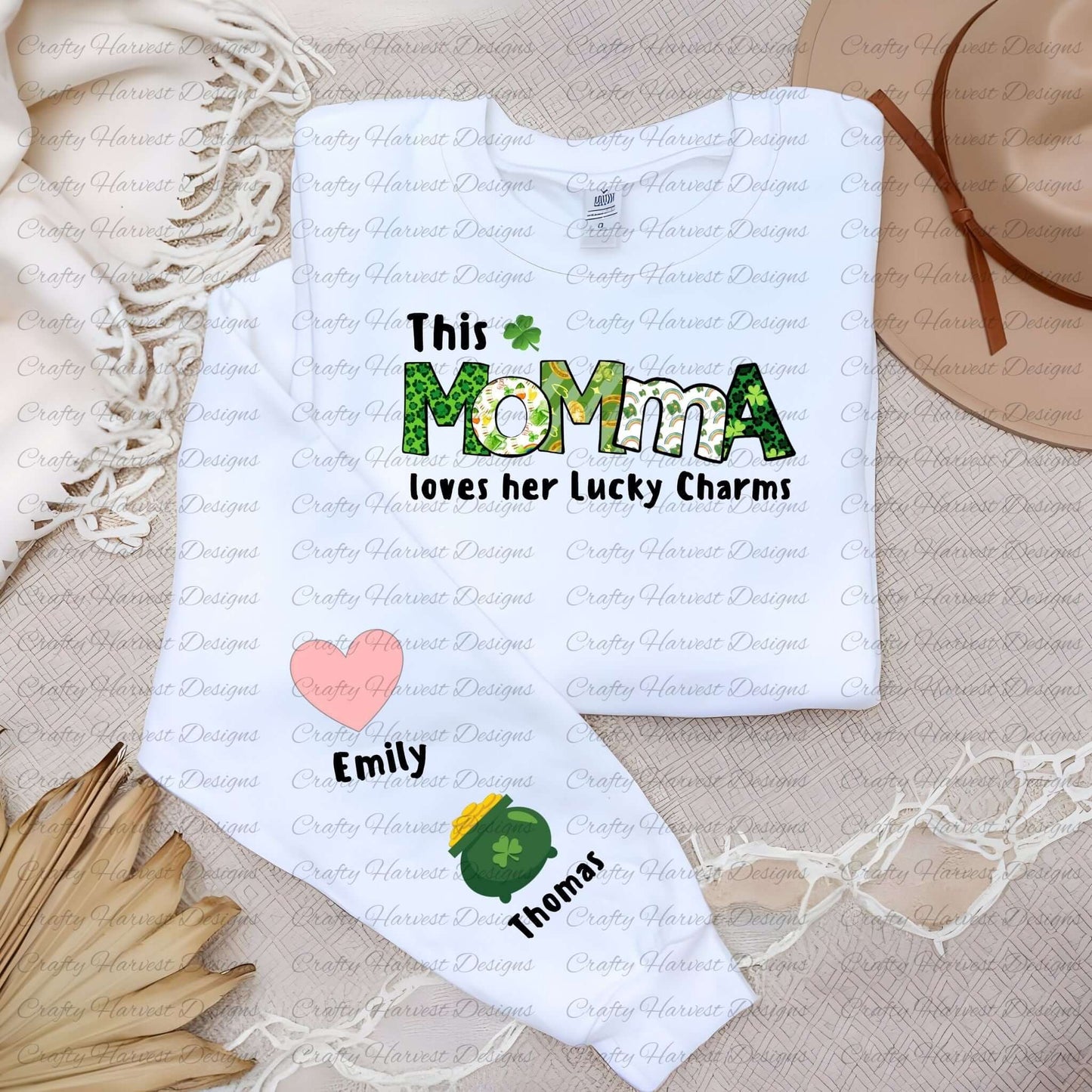 White shirt with a “This MOMMA loves her Lucky Charms” design, featuring green-patterned letters and two colorful charm icons with the names “Emily” and “Thomas” along the sleeve.