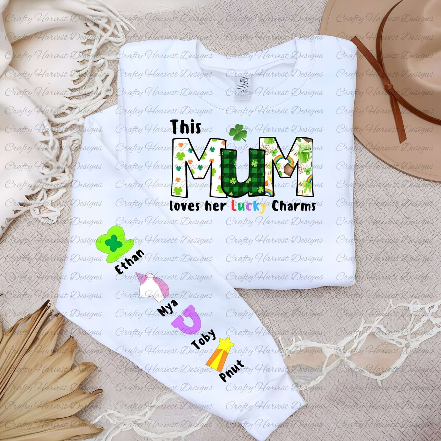 White shirt with a “This MUM loves her Lucky Charms” design, featuring green-patterned letters and colorful charm icons with names along the sleeve.