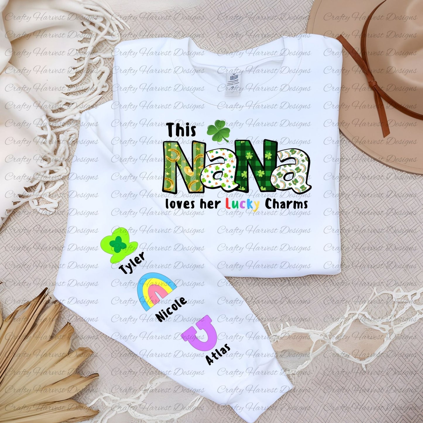 White shirt with a “This NANA loves her Lucky Charms” design, featuring green-patterned letters and two colorful charm icons with the names “Emily” and “Thomas” along the sleeve.