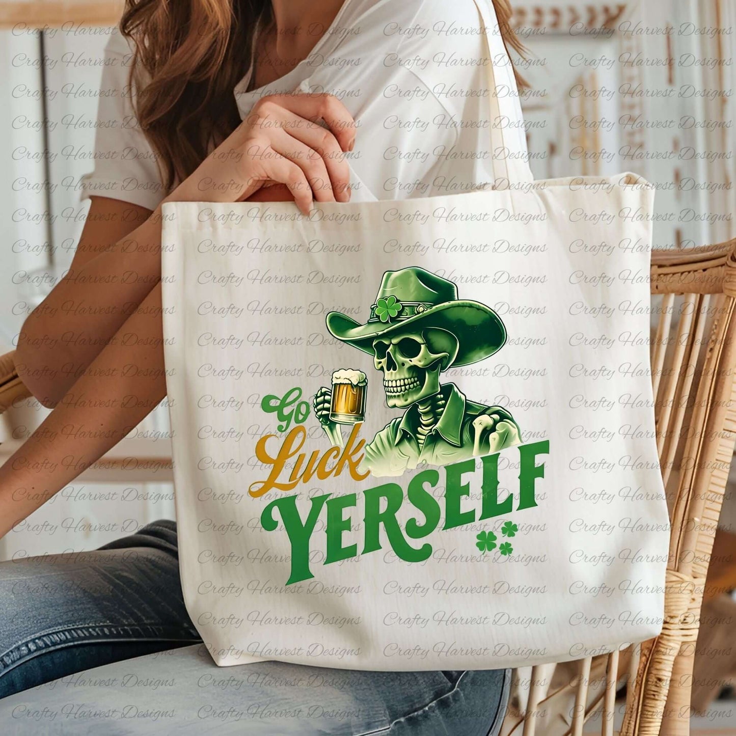 A person wearing a white shirt holds a cream-colored canvas tote bag featuring a green and yellow graphic design. The design shows a skeleton wearing a cowboy hat with a shamrock, holding a beer mug. The text reads “Go Luck Yourself” with two small shamrocks