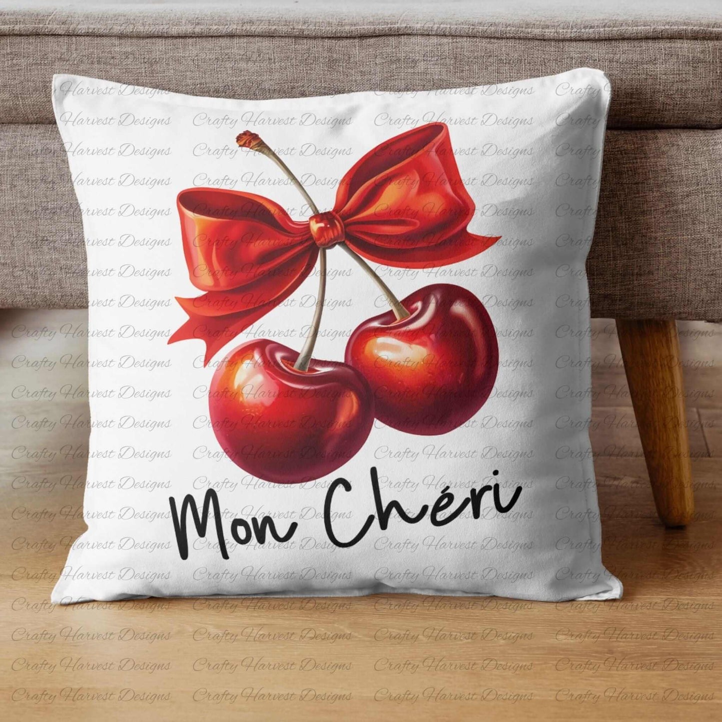 White throw pillow featuring a digital design of two vibrant red cherries tied with a bold red bow, accompanied by the elegant black text ‘Mon Chéri.’ The pillow is displayed on a wooden floor beside a sofa, showcasing its use as a decorative home decor item.