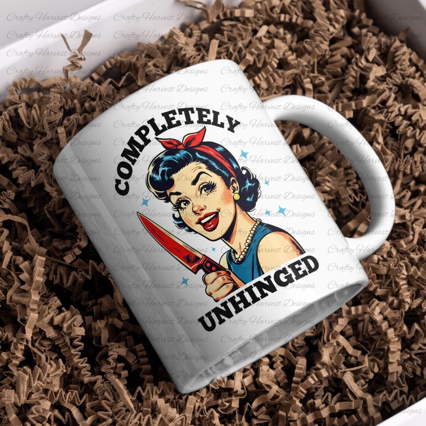 White ceramic mug featuring a retro-inspired digital design of a cheerful woman holding a red-handled knife, accompanied by the bold text ‘Completely Unhinged.’ The mug is nestled in brown shredded paper, showcasing its use as a humorous and stylish drinkware item or gift.