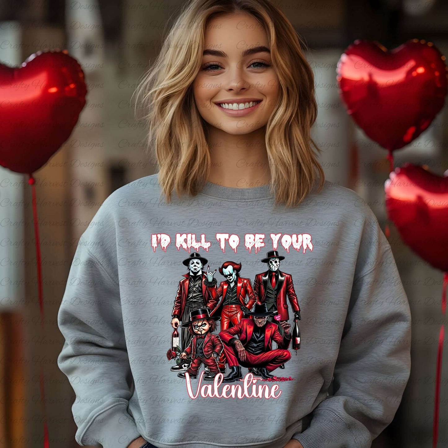 A woman smiling while wearing a light gray sweatshirt featuring a horror-themed Valentine’s Day design with the text “I’d Kill to Be Your Valentine” in dripping and cursive fonts. The design shows a group of iconic horror characters dressed in red suits. Red heart-shaped balloons are visible in the background.