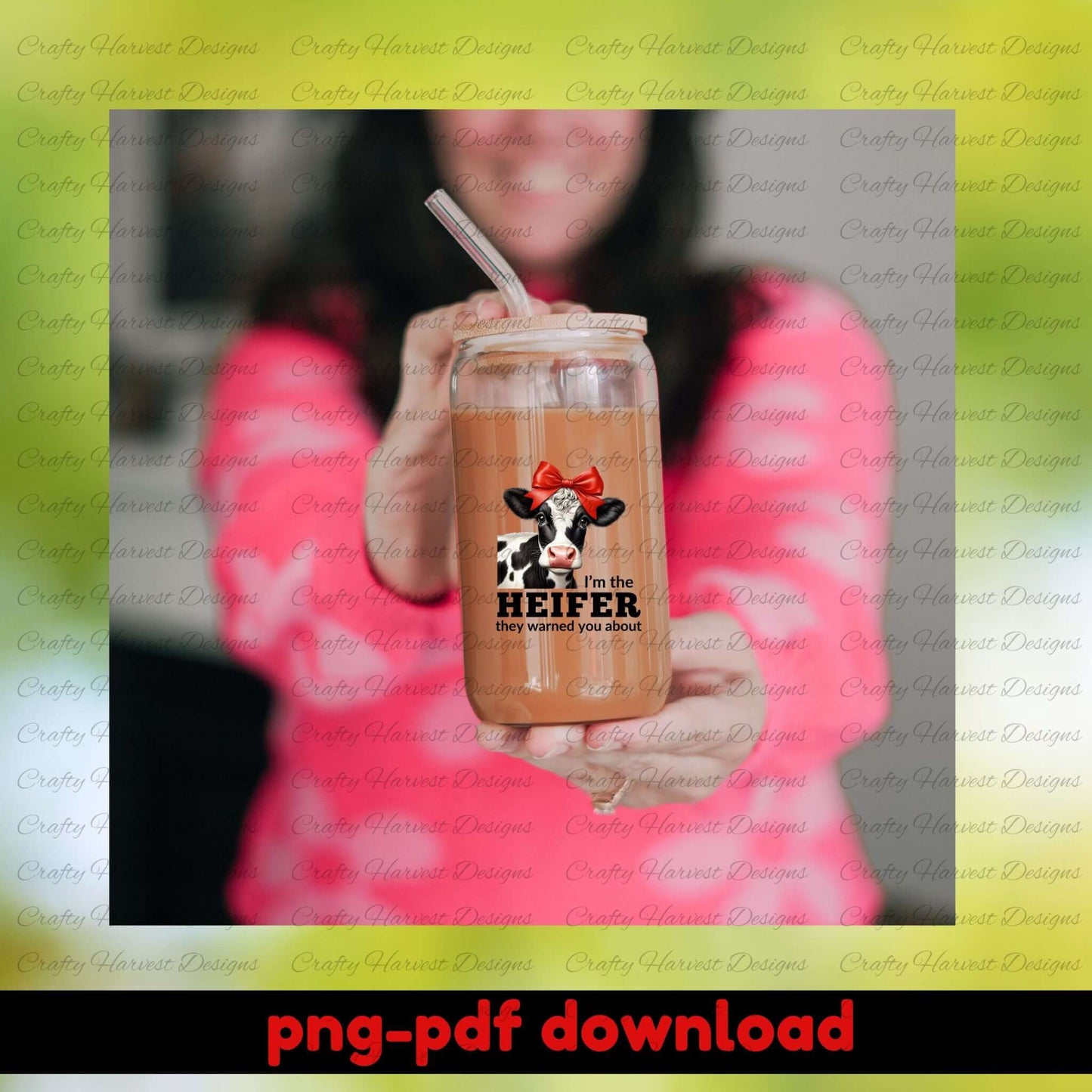 Person holding a glass mug with a cow design and text, against a blurred background.