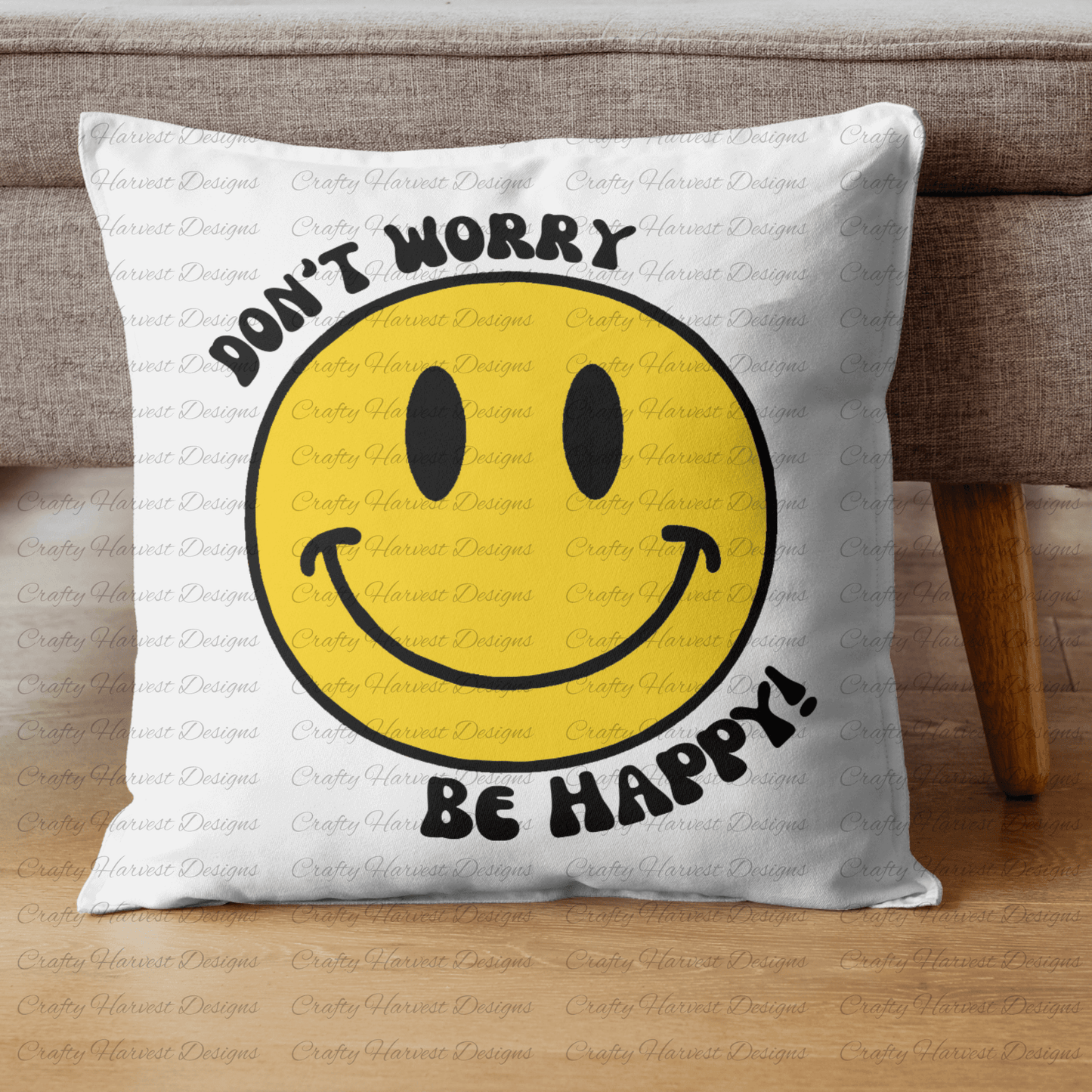 Square throw pillow resting against a couch, featuring a classic yellow smiley face design with the phrase ‘Don’t Worry, Be Happy!’ in black text.