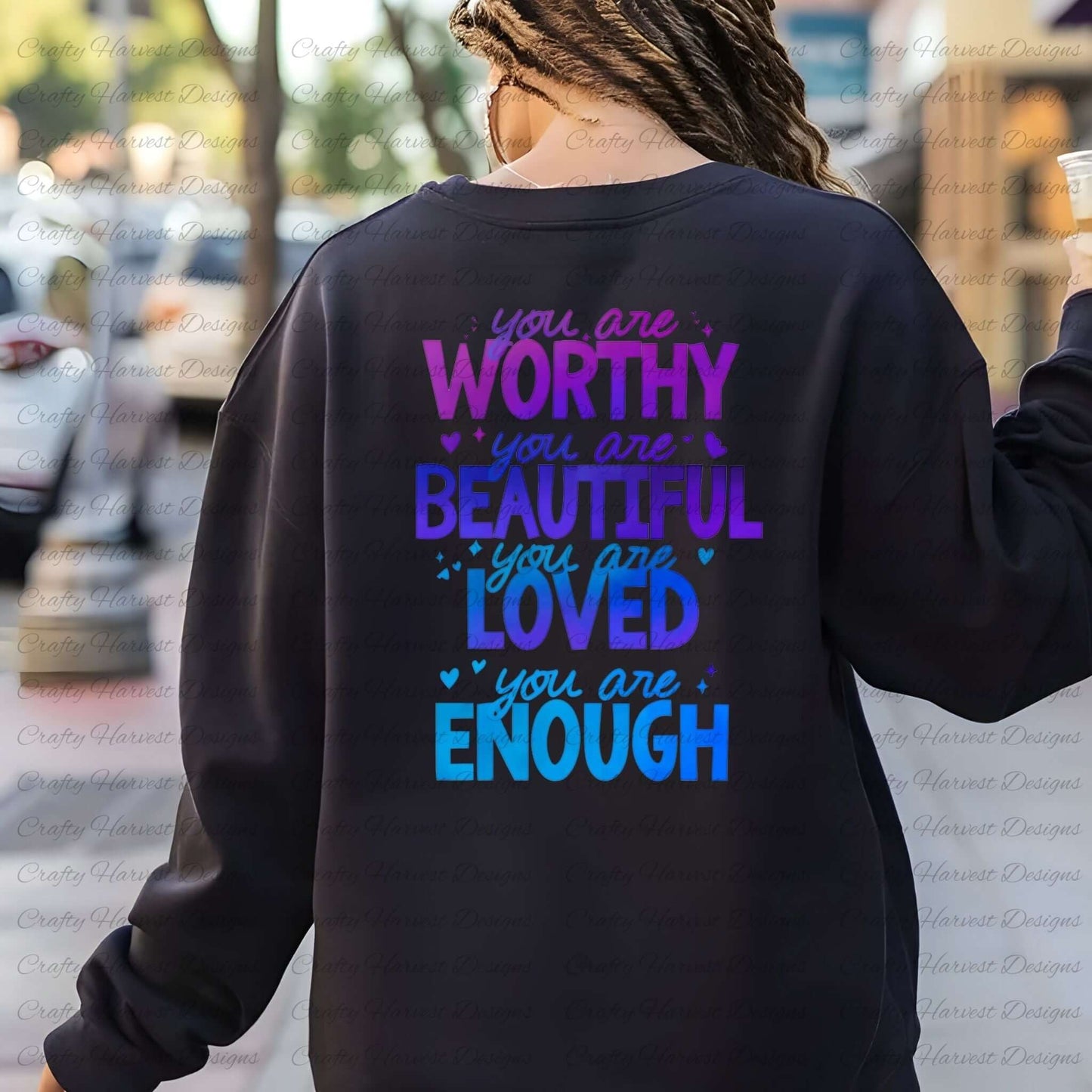 Back view of a person wearing a black sweatshirt featuring the motivational phrase ‘You are Worthy, Beautiful, Loved, Enough’ in a gradient of purple and blue text with heart accents.