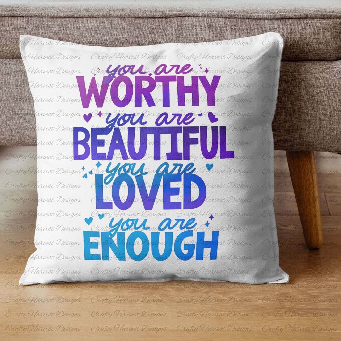 Square white pillow featuring the motivational phrase ‘You are Worthy, Beautiful, Loved, Enough’ in a gradient of purple and blue text with heart accents, placed on a neutral-colored couch.