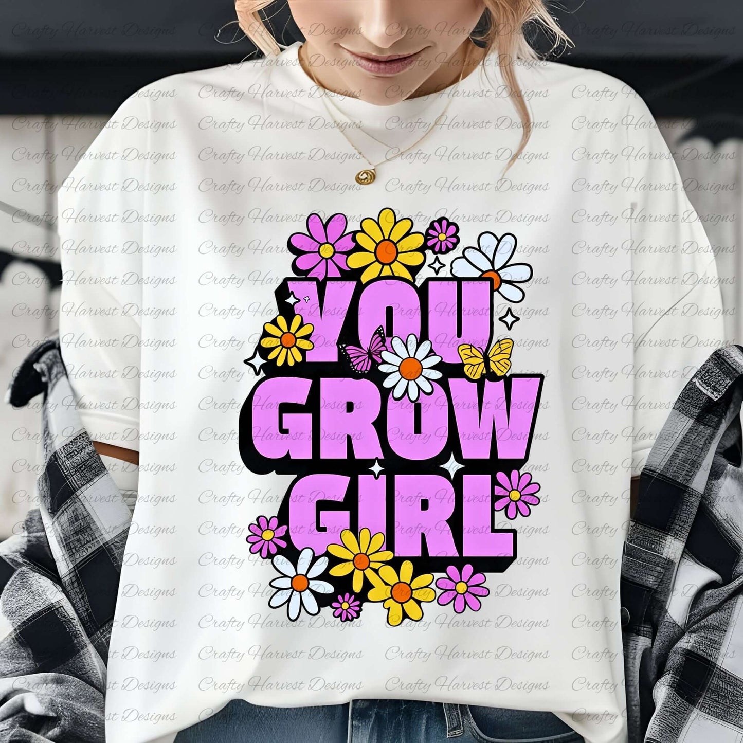 a woman wearing a white t-shirt featuring the ‘You Grow Girl’ design, with bold purple text surrounded by colorful flowers and butterflies. She is layered with a black-and-white flannel shirt and accessorized with a gold necklace.