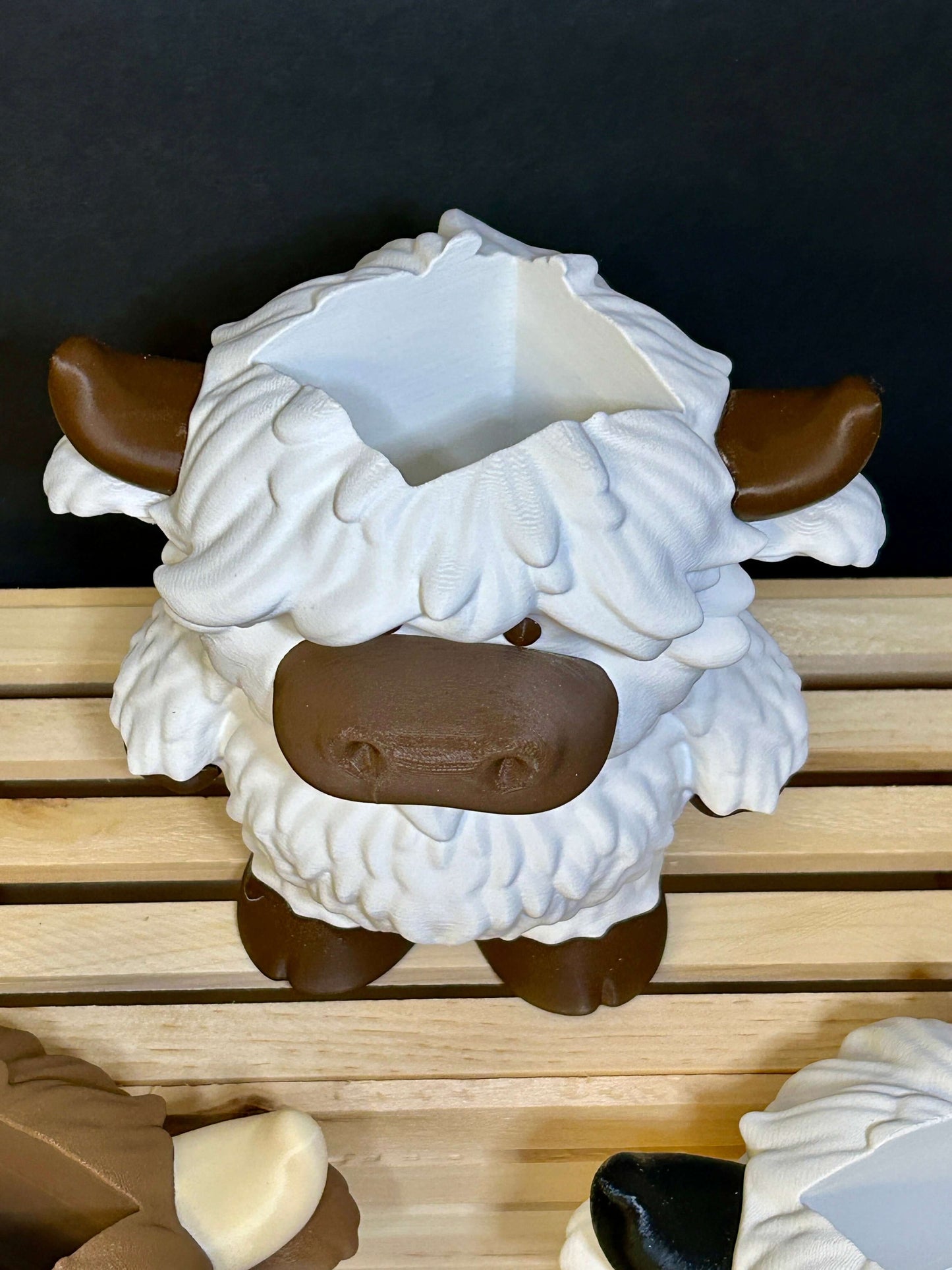 White and brown highland cow soap holder top view. sitting on a wooden box