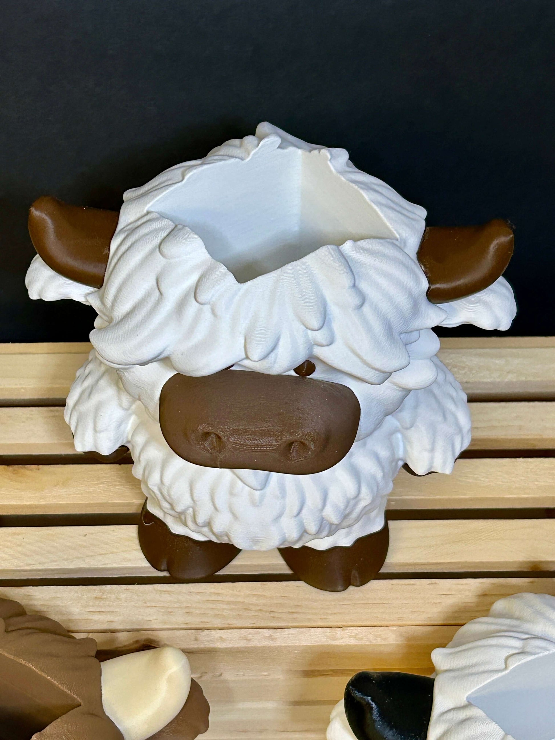 White and brown highland cow soap holder top view. sitting on a wooden box