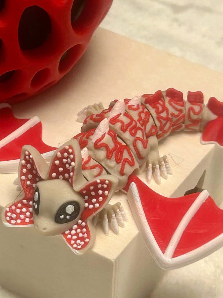 Red and white lizard-shaped object on a beige surface