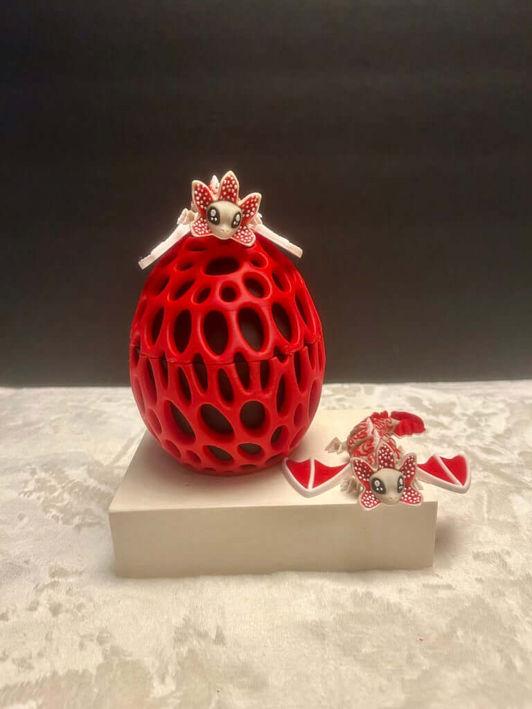 Red decorative egg with a small figurine on top, set against a dark background.