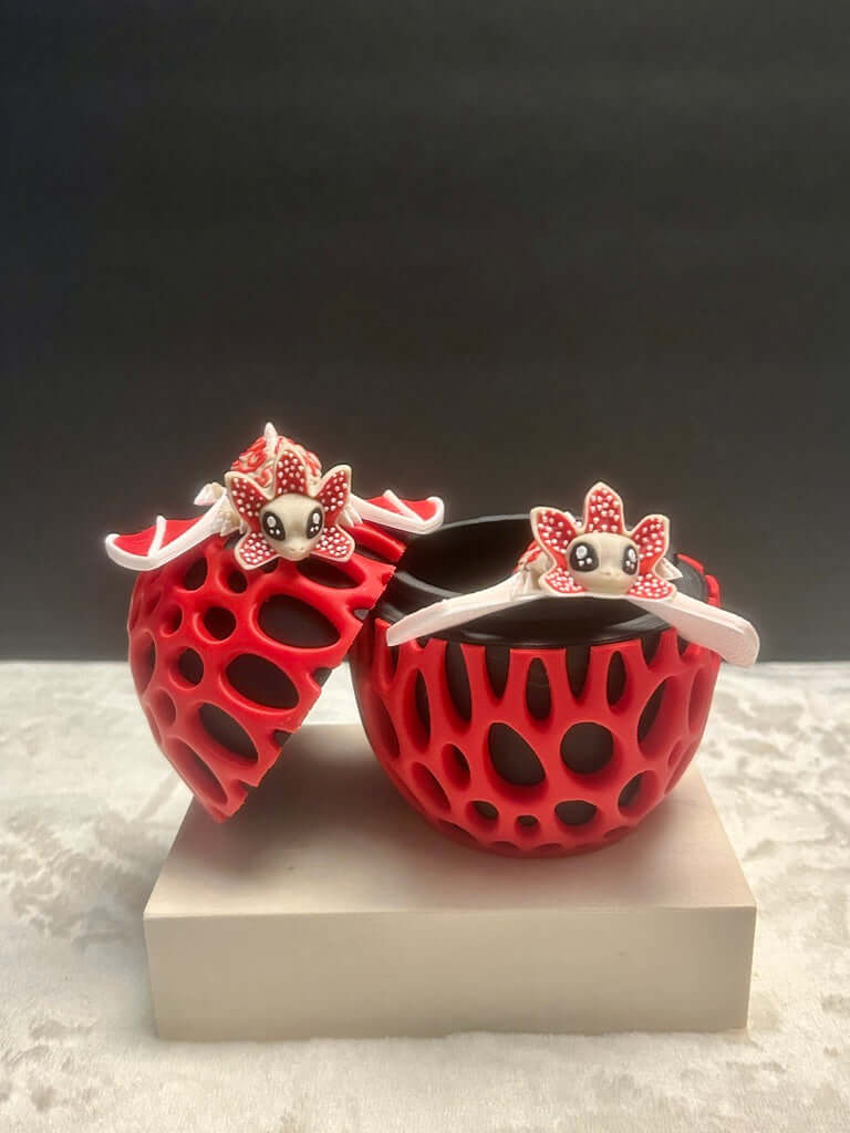 Red and black decorative items with cartoon faces on a white platform against a dark background