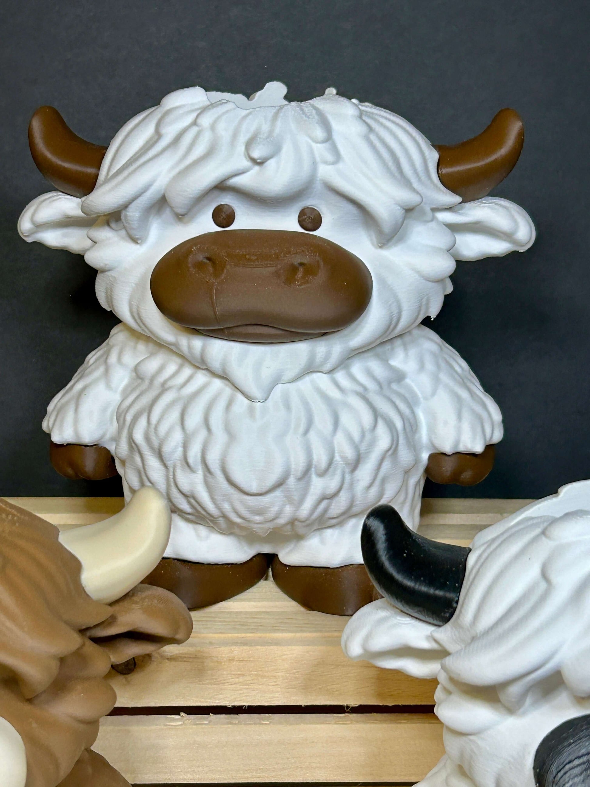 White and brown cow soap holder with brown hooves on a wooden box