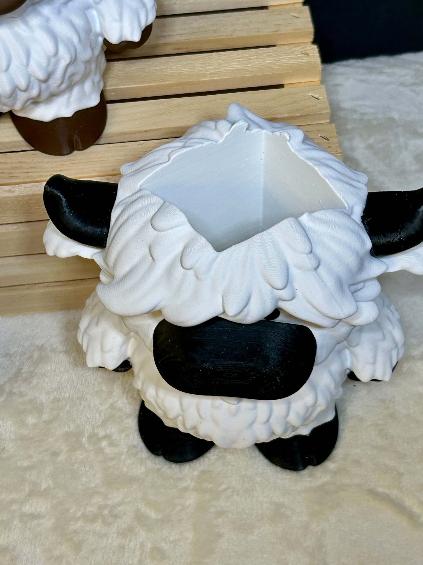 White and black cow soap holder with black hooves on a light cream colored surface