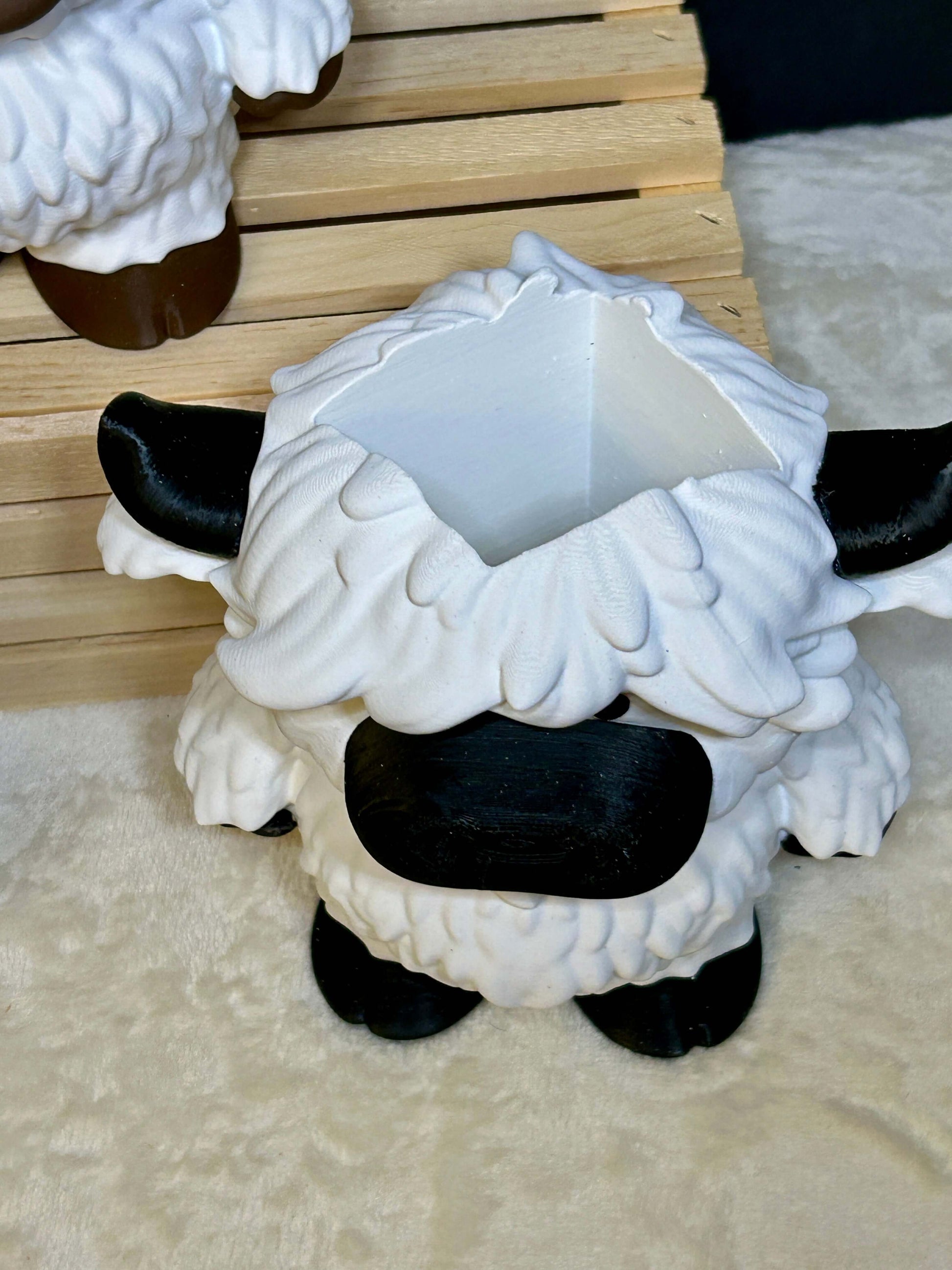 White and black cow soap holder with black hooves on a light cream colored surface